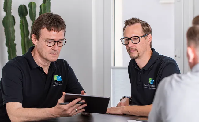 Zahntechniker beraten Zahnarztpraxis zu digitalen Workflows und zeigen Inhalte auf einem Tablet